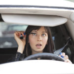 Female driver distracted while applying mascara